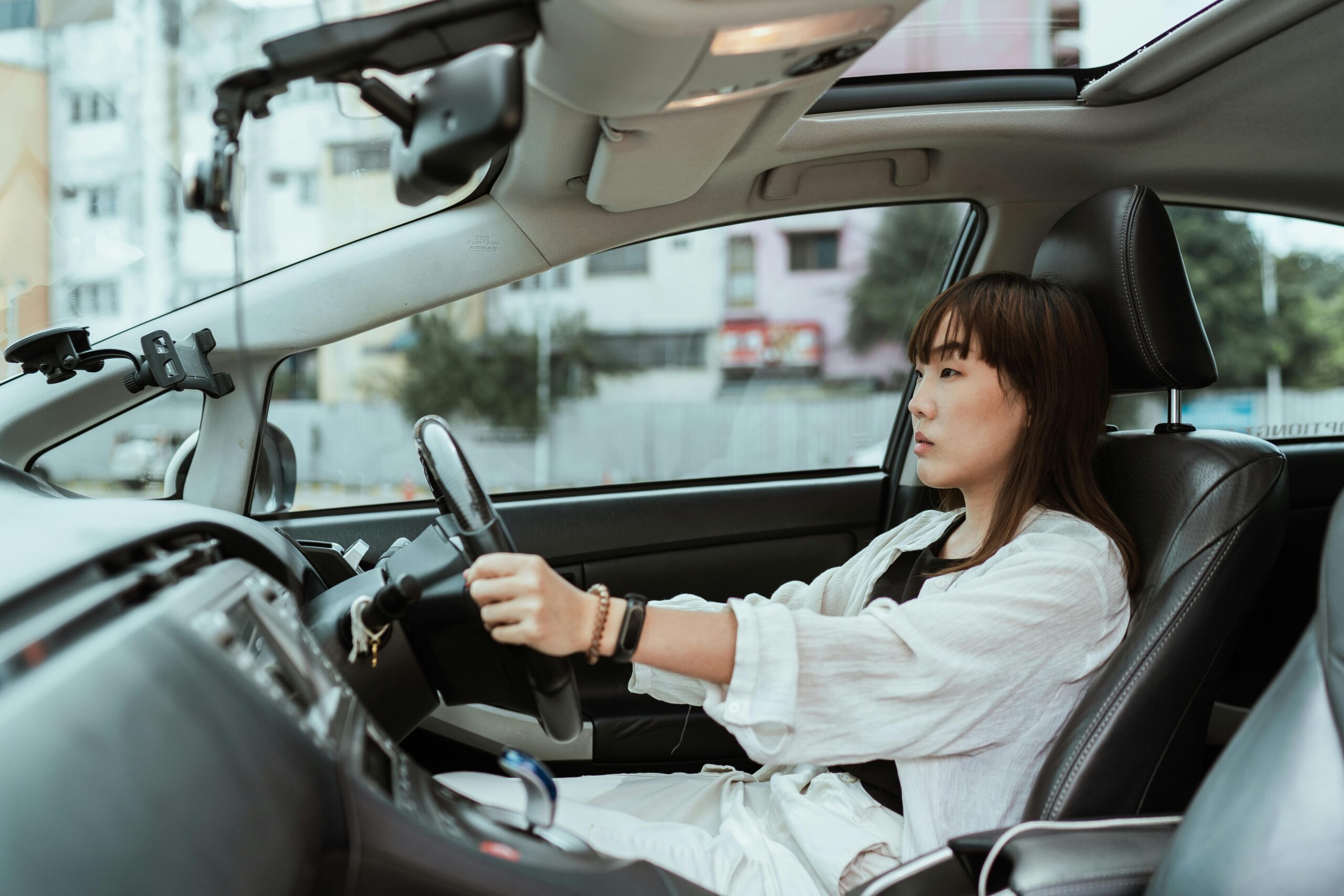 Confident young woman driving in the city, focused and pensive.