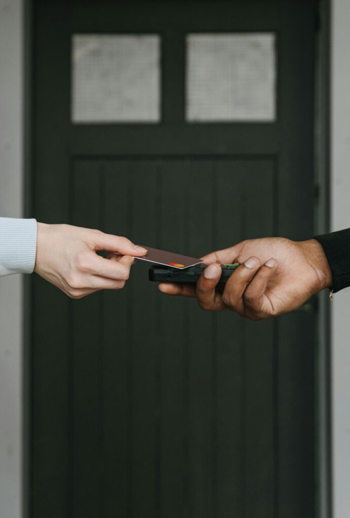 Close-up of hands exchanging credit card for contactless payment, emphasizing cashless transactions.