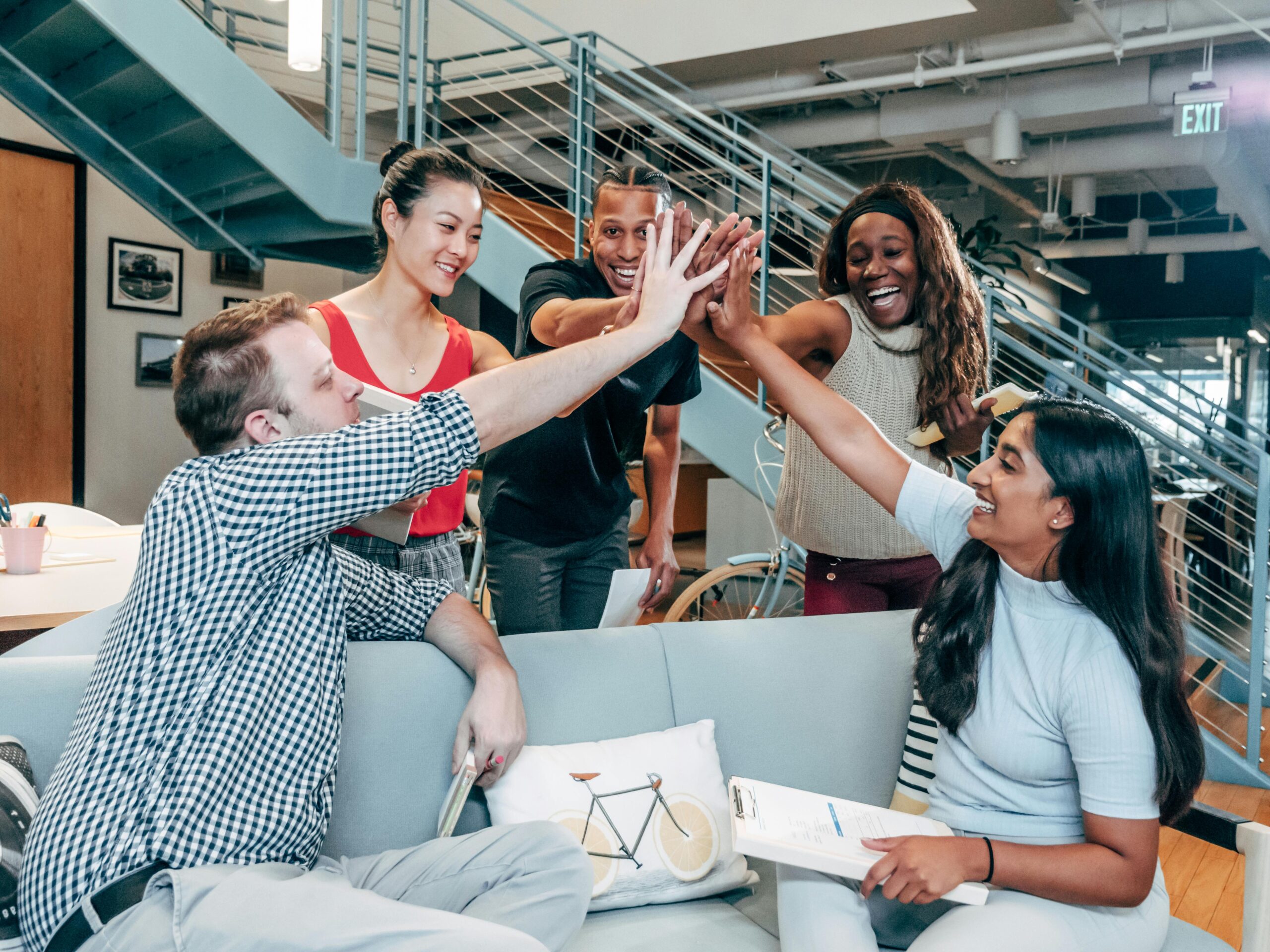 A multicultural office team high-fiving and celebrating a successful collaboration.