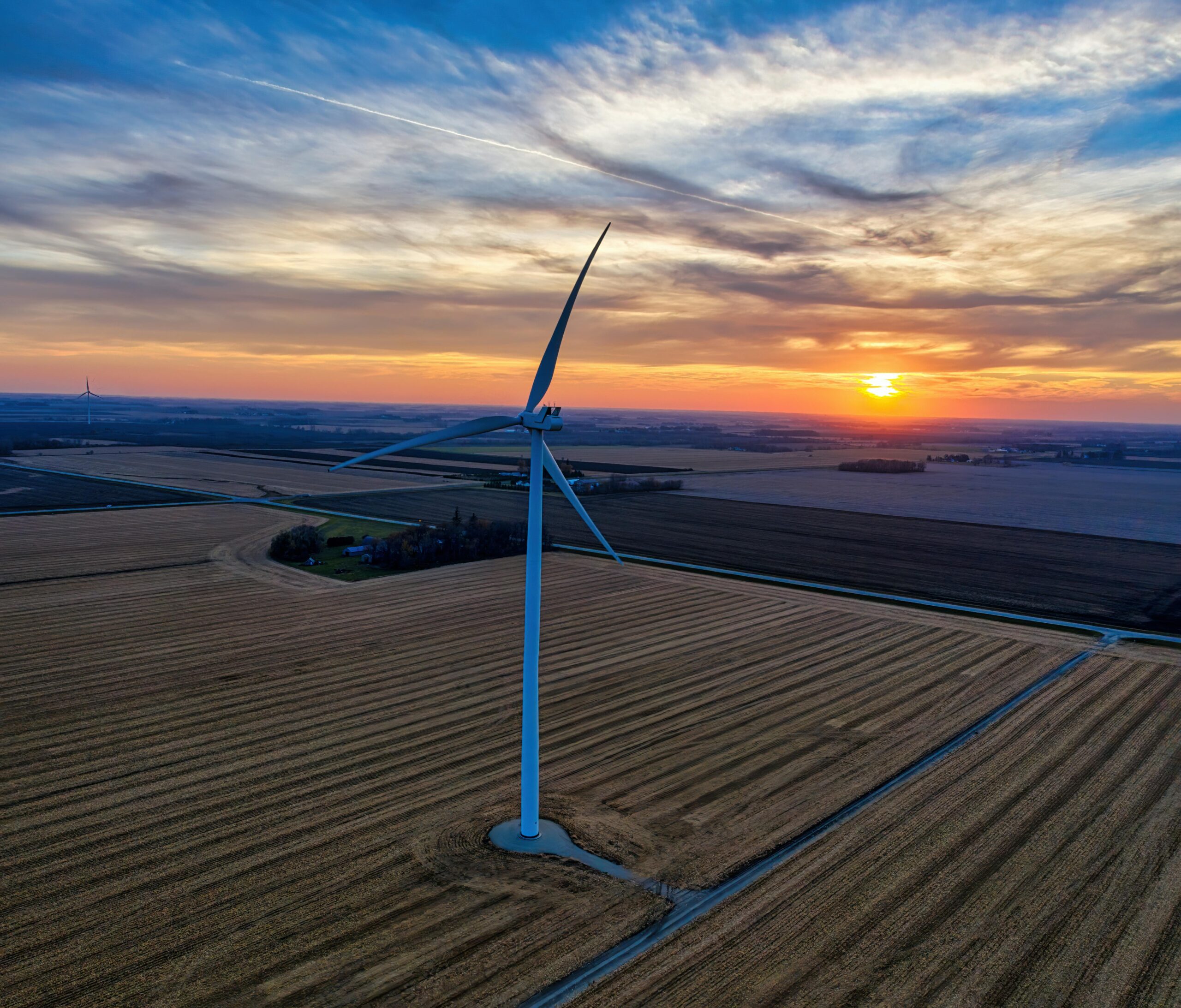 Aerial view of wind turbine in Minnesota field at sunset, showcasing renewable energy.