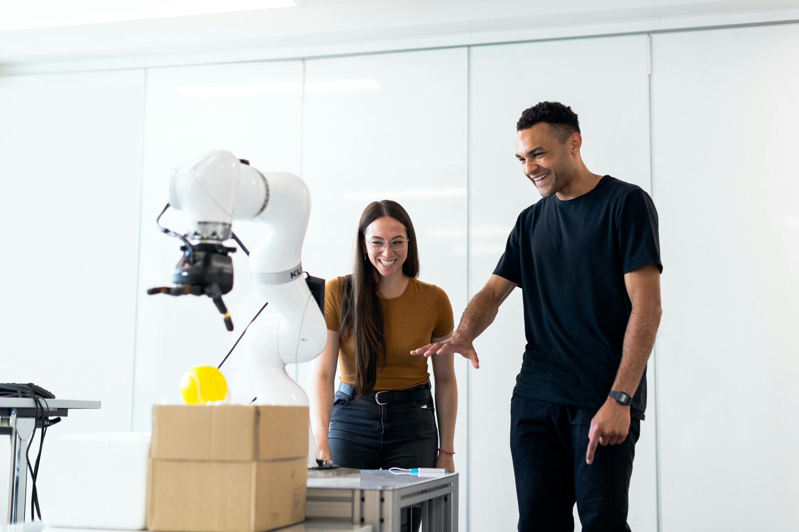 Two engineers collaborating on testing a futuristic robotic prototype in a modern indoor lab.