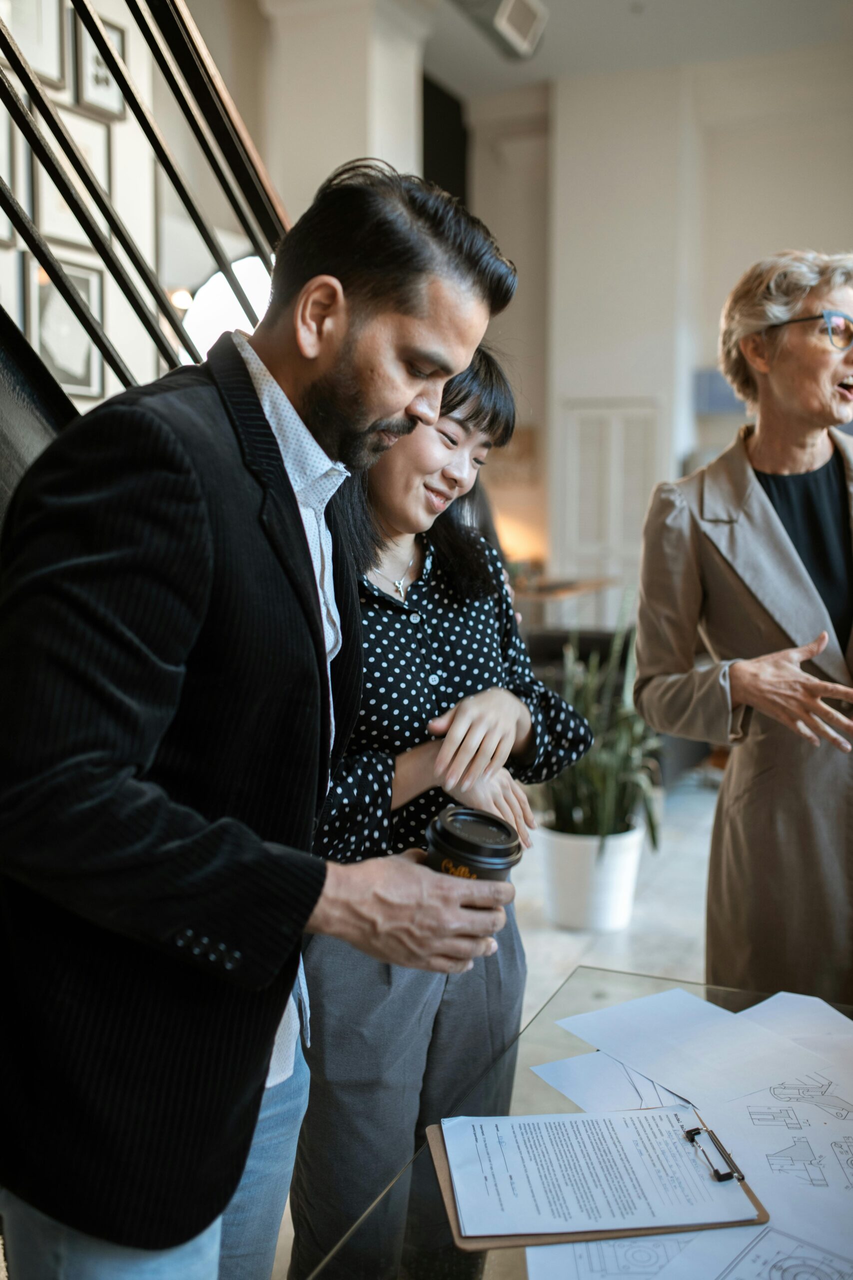 Three adults discussing business plans around a table in a modern office setting.