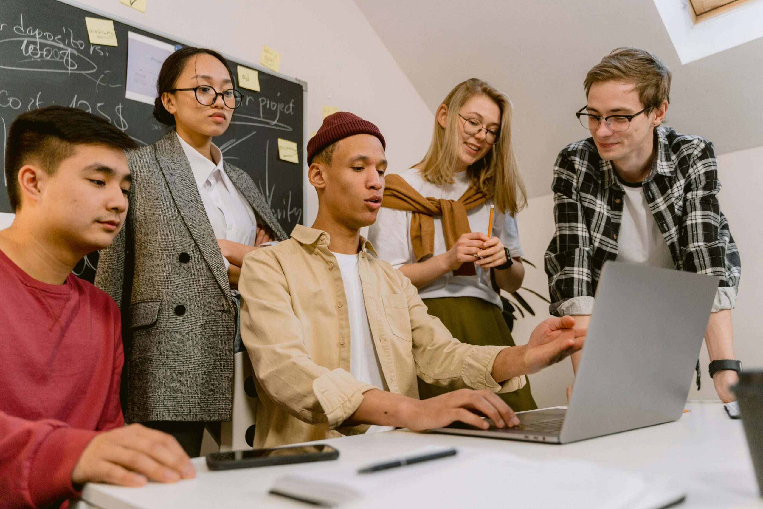 A diverse team of young professionals brainstorming with a laptop in a modern office.