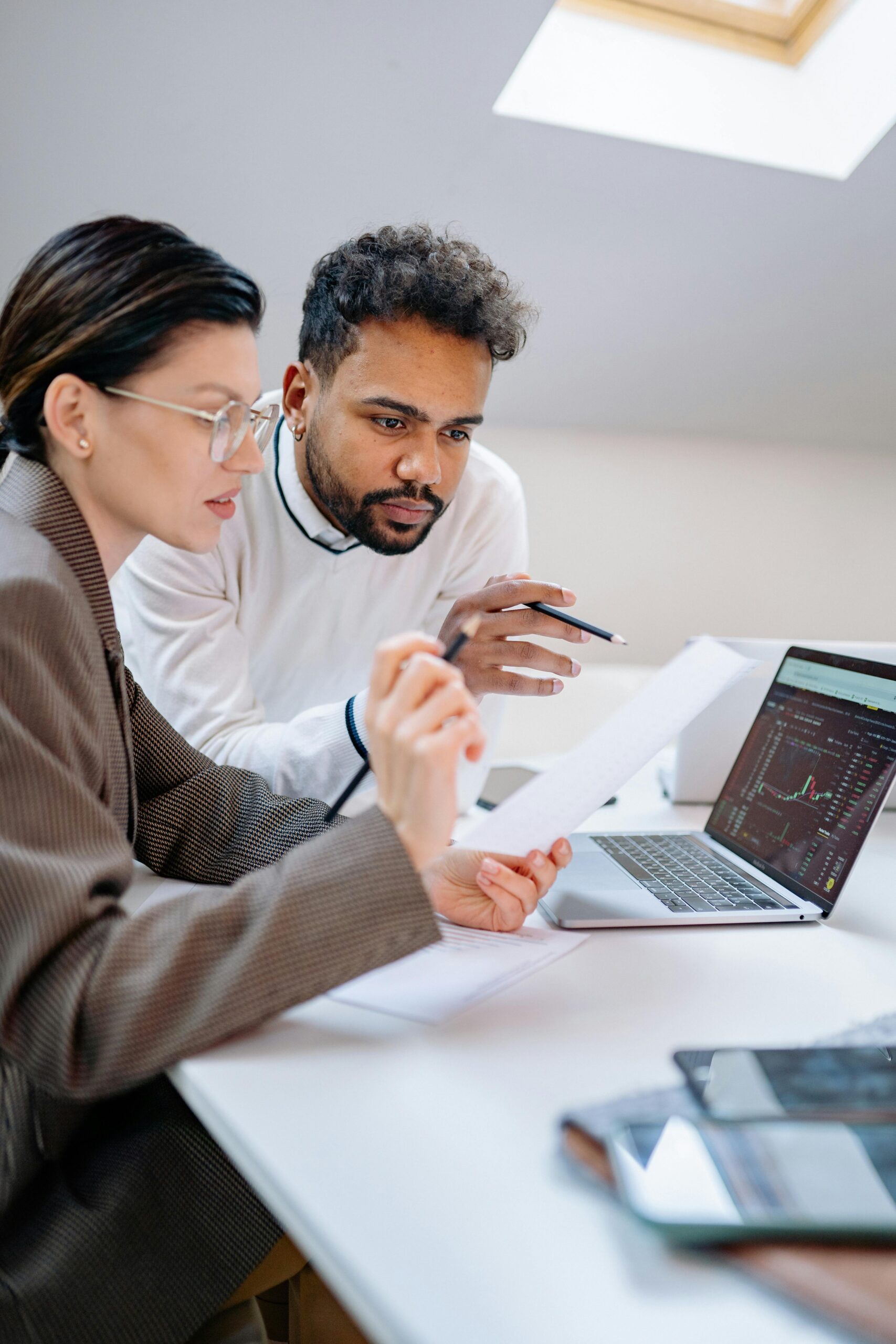 Two colleagues collaborating on financial data analysis in a modern office environment.