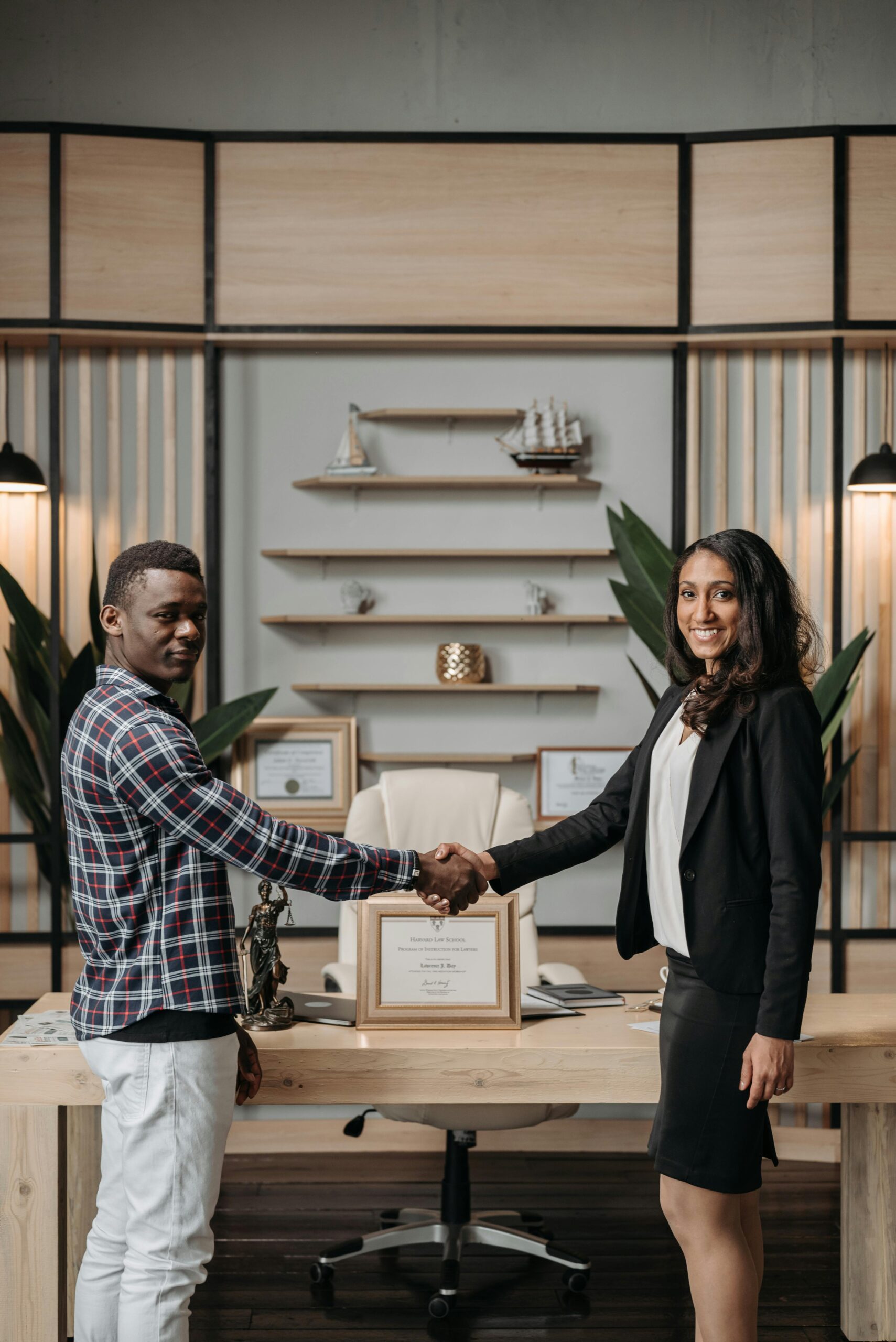 Business professionals shaking hands in a modern office, symbolizing collaboration.