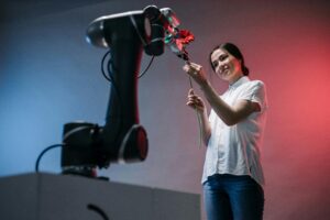 A woman and a robot arm collaboratively holding a flower, symbolizing technology's gentle touch.