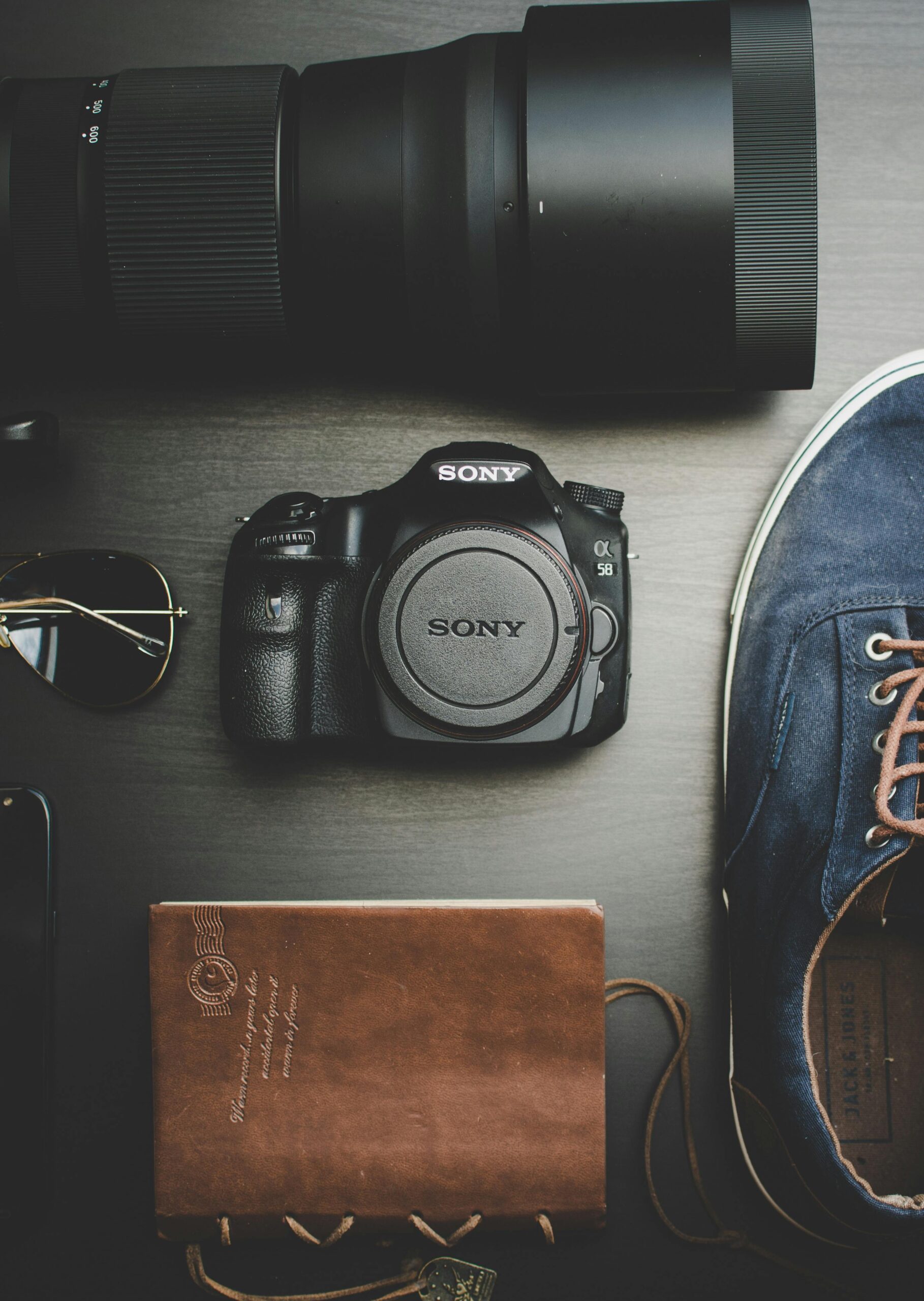 Stylish flatlay of travel essentials including camera, notebook, and sunglasses.