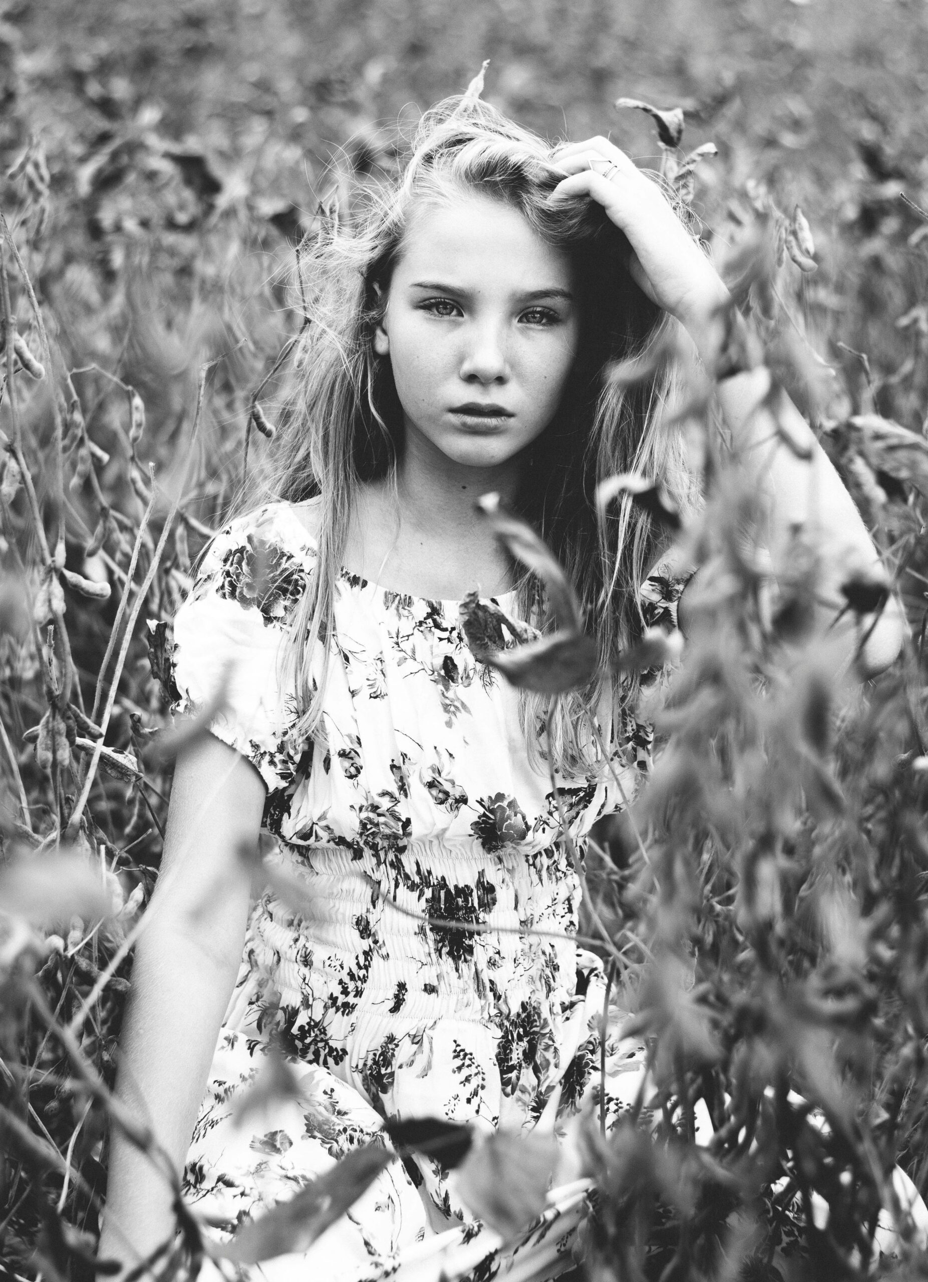 Artistic black and white portrait of a young girl in a field, evoking a sense of calm.