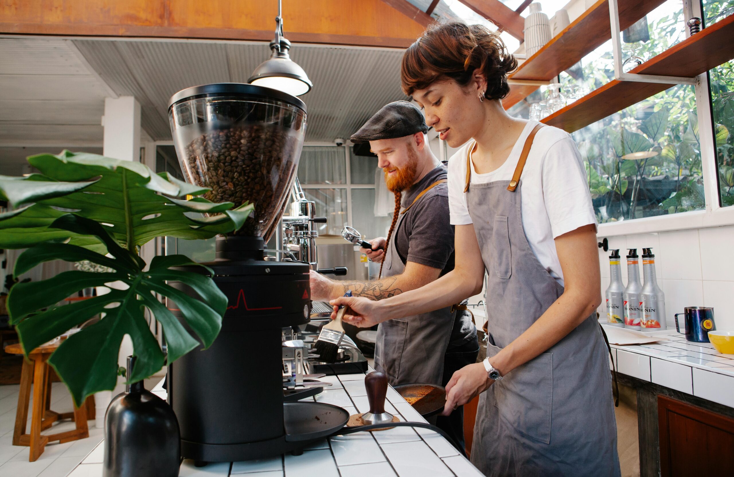 Coffee shop employees grinding fresh coffee beans and preparing espresso.