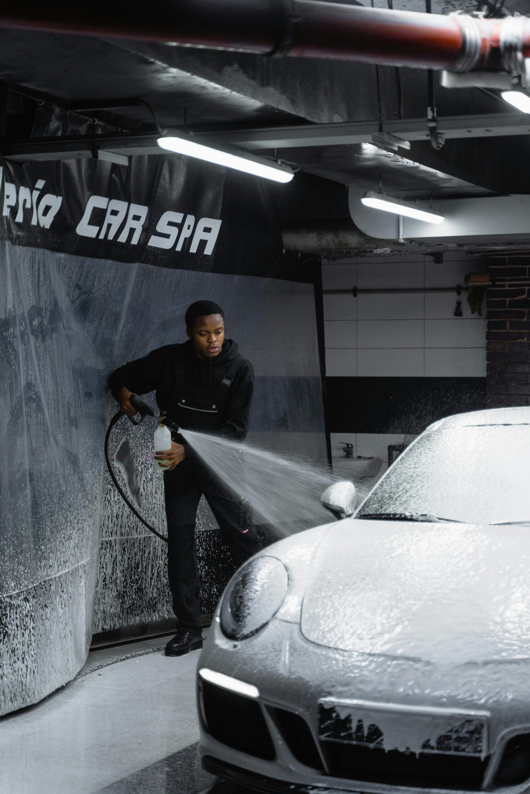 Efficient car wash by a skilled worker at a modern garage, ensuring a spotless vehicle.