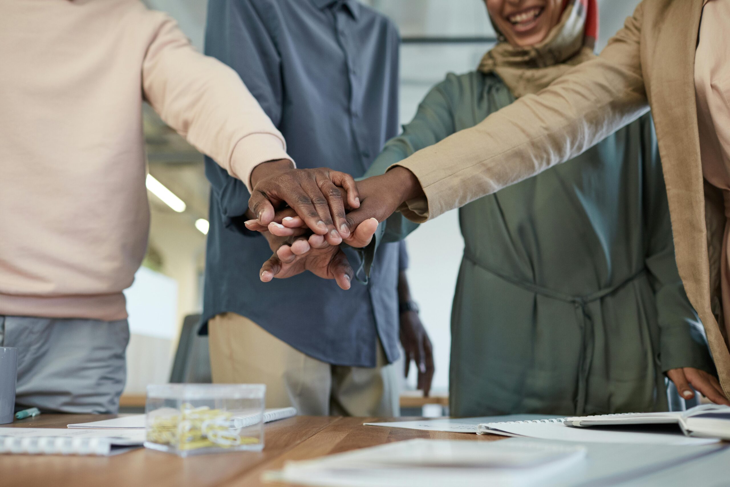 A diverse group of colleagues stacking hands, representing teamwork and unity in an office environment.