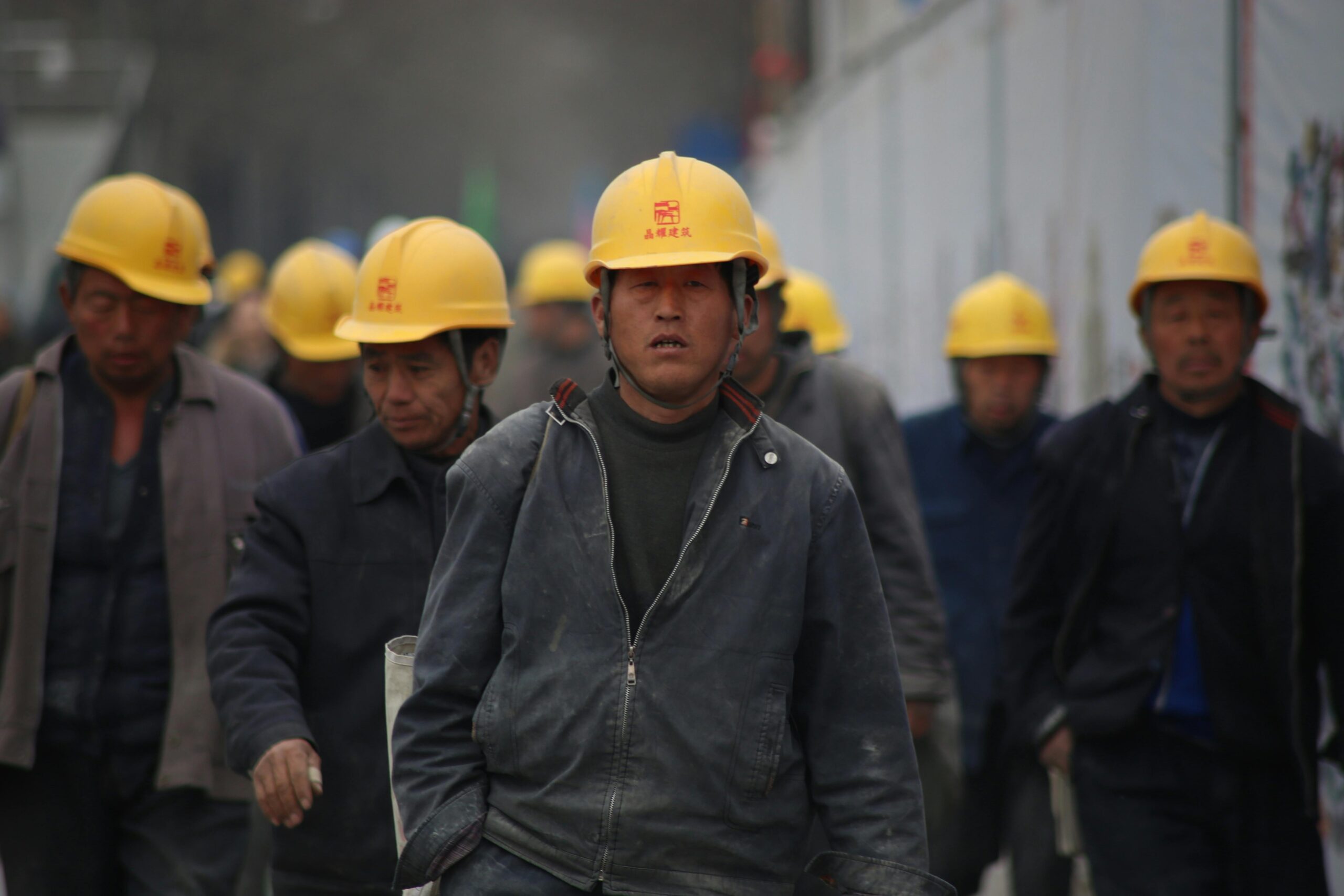 Construction workers in hard hats walking at a site, highlighting teamwork and safety.