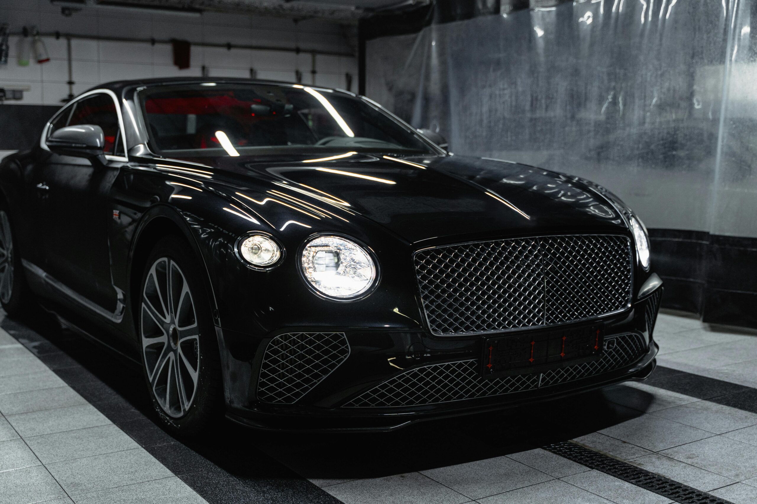 Sleek black luxury car in a modern indoor car wash setting, showcasing elegance and sophistication.